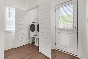 A small room with a washing machine and dryer built into the cabinetry.